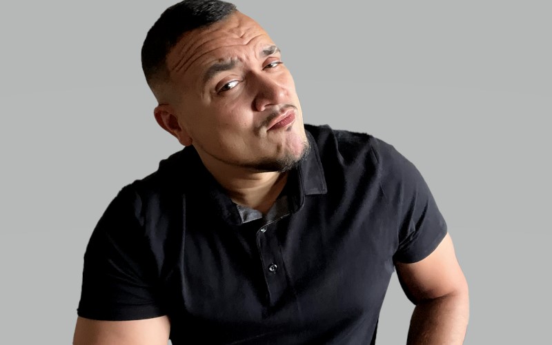 Portrait of a person with a quizzical expression, wearing a black polo shirt against a neutral background.